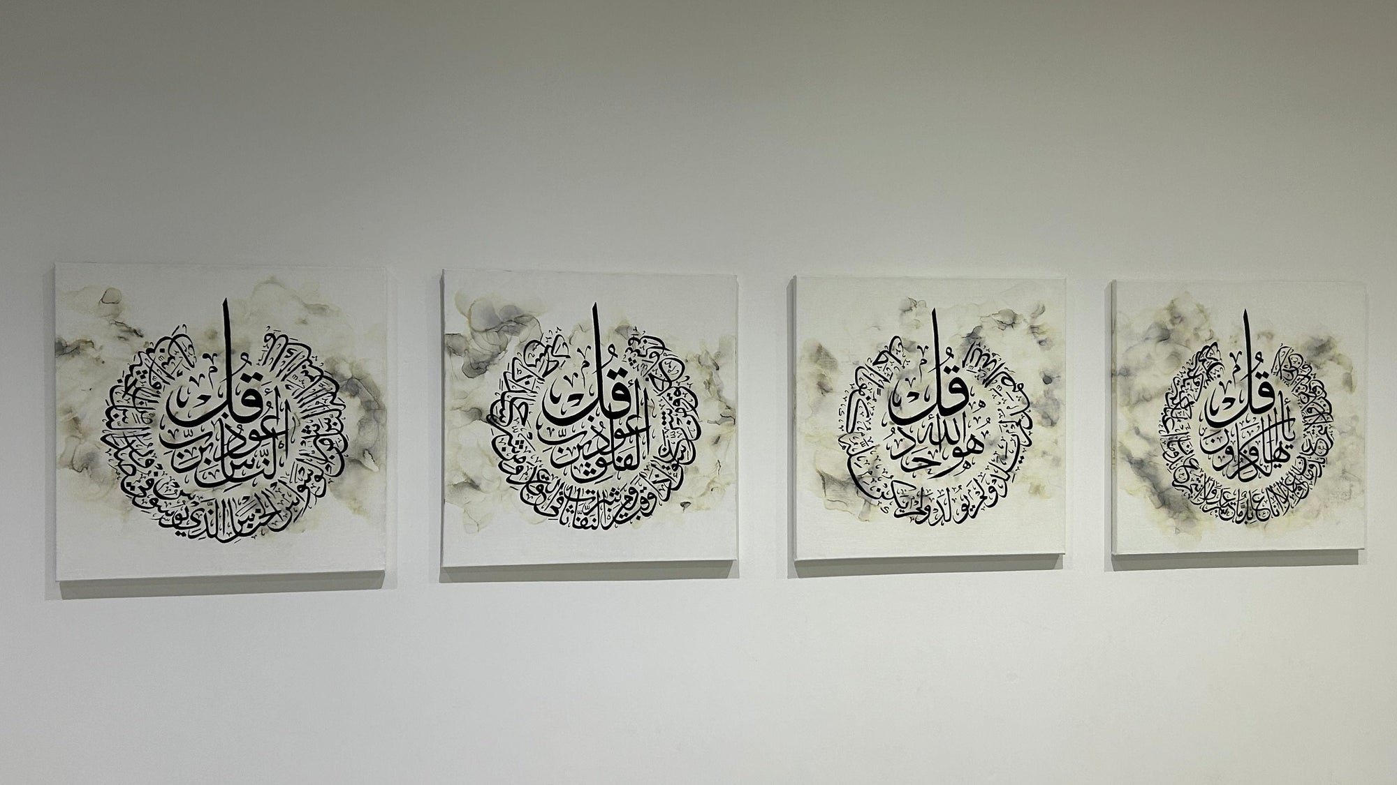 Four framed pieces of calligraphy art on a white wall.